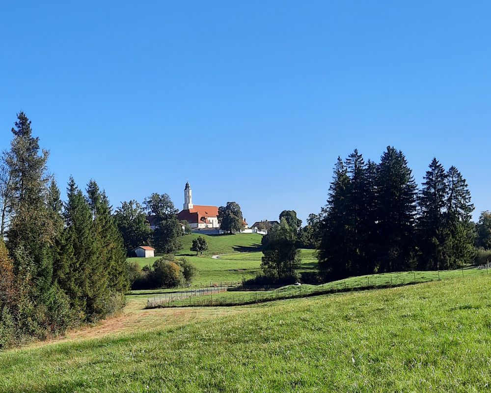 Wiese und blauer Himmel mit Kloster Reutberg